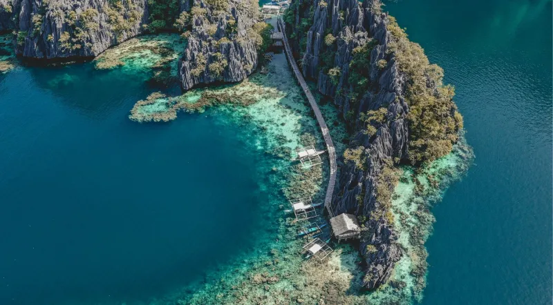 Aerial view of the Kayangan Lake boardwalk staircase on Coron Island, surrounded by deep blue water and limestone karst